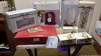 Full view of boxed gift items including vase, clock, tea set, and assorted boxes on table