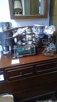 Overview of all items on a wooden dresser including the metal tin man, two soda can biplanes, sailboats, car clock, and Mercedes-Benz model car in box.