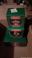 Stack of three green boxes labeled Christmas Around the World with images of teapot, figurines, and cookie jar