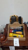 Wooden CD holder containing five assorted flashlights in various colors and sizes, set on a wooden table.