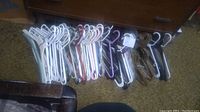 Full lot of various metal and plastic clothes hangers in assorted colors laid on carpet near wooden furniture.