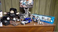 View of the full lot showing Harley Davidson lamp, Motorcycle Monkey plush, die cast motorcycles, wallet, and watch arranged on a table against a wood paneled background.