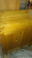 Top-front side view of the IKEA wooden cabinet showing the natural wood grain, scratches, and overall condition.