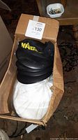 Box of white and black disposable painter hats, showing stacked hats inside
