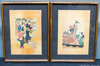 Two framed Asian prints side by side with bamboo-style frames on a dark background