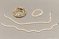 Overview of all jewelry items: two white baroque pearl chokers and one multicoloured faux pearl stretch bracelet.