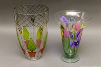 Side view of two hand-painted glass vases: one clear with geometric and plant design, and one thick pedestal vase with colorful floral painting.