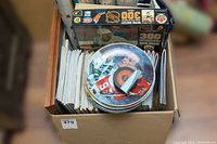 Box containing various decorative plates with hockey player images, a boxed Wayne Gretzky collectible, and documents or magazines stacked.