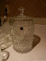 Cut glass ice bucket with intricate cut patterns and faceted knob lid, showing detailed starburst and geometric cuts.