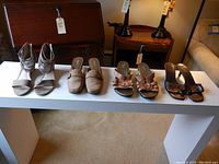 Four pairs of assorted women's shoes on display, showing different angles and styles including heels and flats.