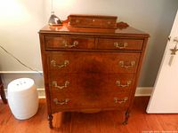Front view of dresser showing five drawers with ornate brass handles, built-in valet drawer on top, and Bombay music box on top of the dresser