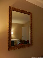 Full view of the rectangular gold painted wood framed mirror hung on a beige wall showing the size and frame detail in a room setting.