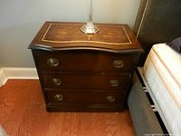 Front view showing the full nightstand with three drawers and gold detailing on top.