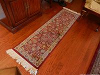 Full view of the burgundy bordered tapestry runner laid out on wood floor, showing length and pattern.