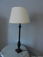Full view of table lamp showing black wood base and white fabric shade