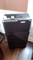 Front and top view of the electronic air purifier showing grill and remote control on top.
