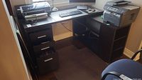 Full view of two-piece dark wood corner desk with printer and computer accessories on top.