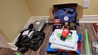 Wide view of lot showing backpack, folded sheets, blankets, a Spider-Man mug, Groot figurines, and part of Captain America costume.