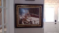Full view of framed winter landscape painting showing house, snow, fence in black and gold frame