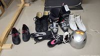 All items arranged on floor showing curling shoes, ski boots, figure skates, helmet, goggles, water shoes, hockey skates.