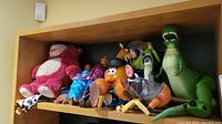 Shelf with Toy Story characters including Lotso plush, Woody, Buzz Lightyear, Rex dinosaur, and Mr. Potato Head.