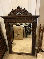 Full view of the rectangular mirror with carved oak frame showing floral border and crest