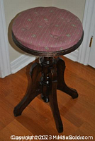 Angled view of walnut wood piano stool with height adjustable rotating seat