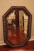 Full view of the hexagonal mirror showing the frame and reflective glass surface leaning against a wall.