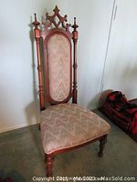 Front view of carved walnut prayer chair with upholstered seat in pale fabric with subtle wave pattern