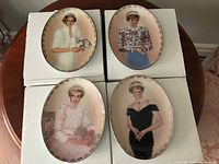 Front view of four Princess Diana collector porcelain plates on boxes, showing detailed portrait artwork and condition.