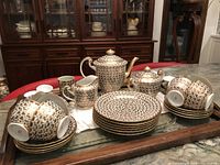 Full set arranged on wooden tray showing all items included in the lot such as teapot, sugar bowl, milk jug, multiple cups, saucers, and plates with distinct floral pattern and gold detailing.