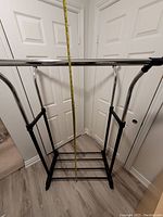 Adjustable double hanging clothing rack with tape measure showing height and base details.