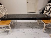 Front view showing rectangular granite slab horizontally placed across two chairs, illustrating size and thickness.
