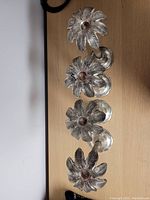 Top view showing the detailed palm leaf design at the candle holder cup, four similar candlesticks lined up vertically.