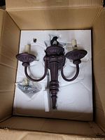 Boxed metal wall sconce with two lamp arms and decorative design, viewed from above showing entire fixture with wiring and mounting hardware.