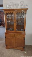 Front view of vintage maple china cabinet with glass display doors and storage below