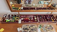 Wide view showing three trays with assorted costume jewelry including bracelets, earrings, and a locket with chain.