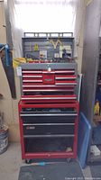 Full view of red Craftsman two-piece locking tool chest with top chest and bottom roller cabinet, tools visible in open drawers