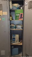 Photo of locker shelves with various boxed and unboxed hardware tools including a double action sander, battery charger, and motorized grinding tool.