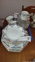 Stack of octagonal plates, tea cups, and saucers with blue and gold floral decoration from Momoyama Imperial pattern fine china.