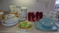 Overall view of Pyrex dishes, Corelle plates, red goblets, pressed glass pieces, aqua bowl and tray