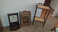 Photo of the wooden 30-day wall clock, the wooden hanging cabinet with glass door, and the wooden cane shelf with two cane shelves.