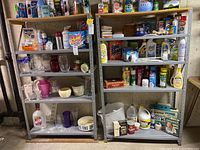 Two complete metal storage shelves in basement with various household items on shelves (not included). Shelves have a gray metal frame with pressboard tops, showing signs of dust and use.