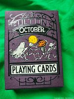 Purple box featuring 'Fulton's October Playing Cards' text with dancing skeleton and pumpkin motif embossed on the front.
