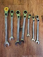 Seven Mastercraft ratcheting wrenches arranged in size order on wooden table showing open and ratchet ends