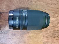 Side view of zoom lens on wooden surface showing 'DX 50-250/4.5-6.3' marking