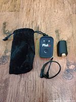 All items laid out on wooden surface: Pluto trigger, adapter, cable, and pouch.