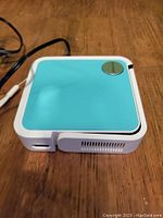 Top view of projector showing teal swappable panel and circular power button