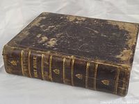 View of the full leather-bound cover showing significant surface wear and scuffing on dark brown leather.