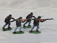 Four toy soldier figurines posed with rifles on green bases, representing 1960s Union troops in Civil War uniforms.